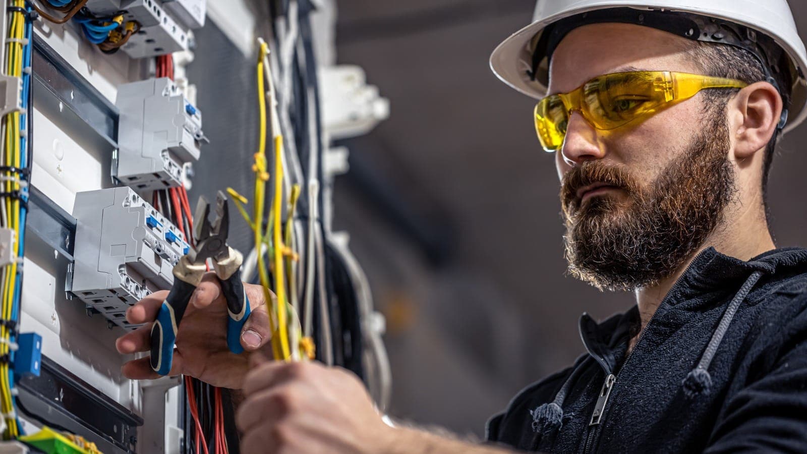 Electrician in safety gear working on a residential electrical switchboard