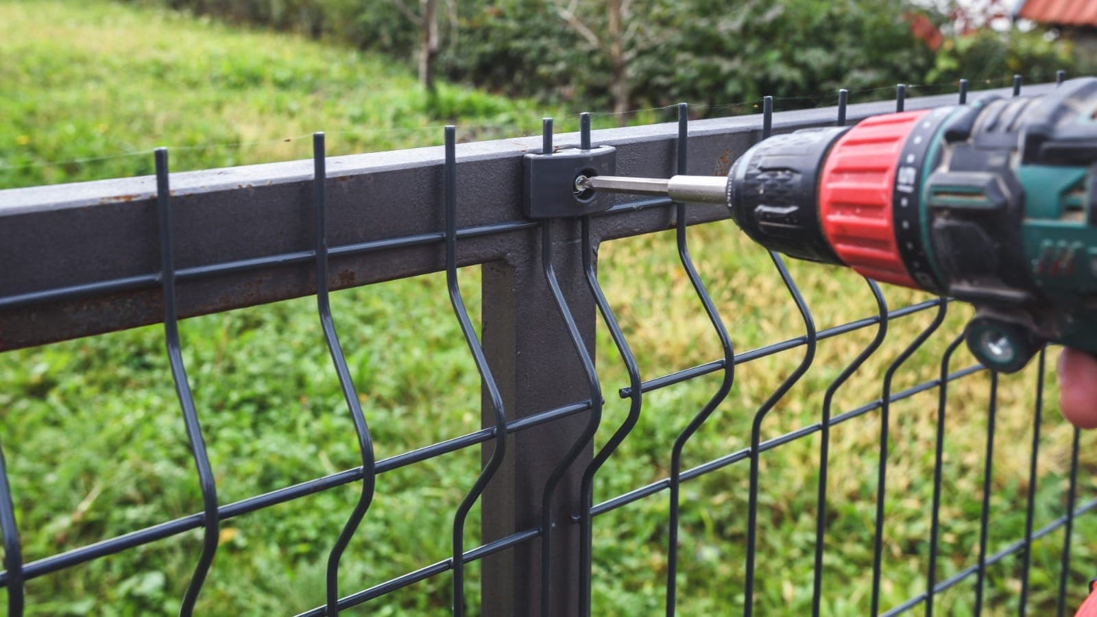 Cordless drill being used to repair a residential mesh fence