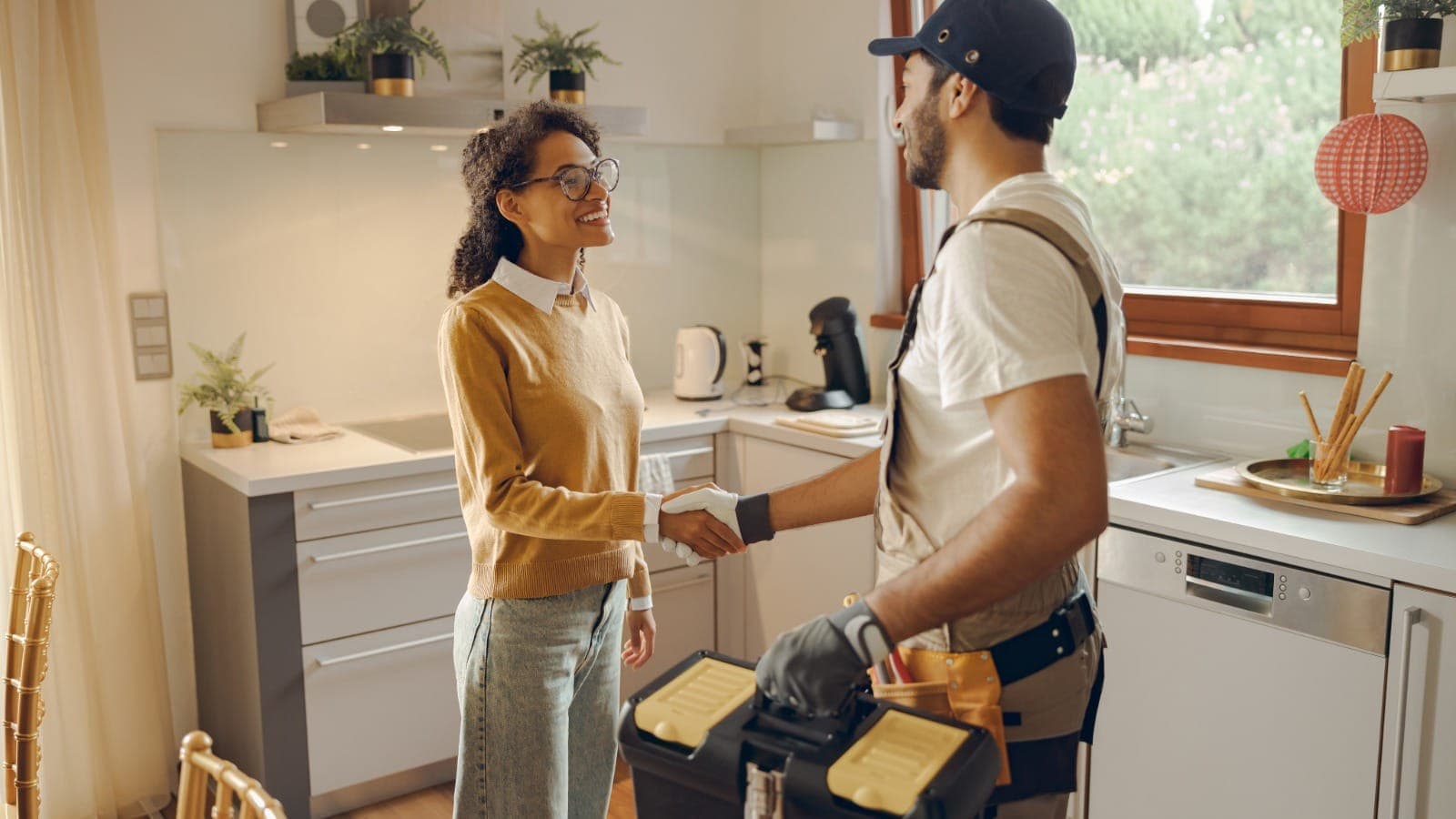 Handyman in a residential kitchen with a toolbox, meeting a customer