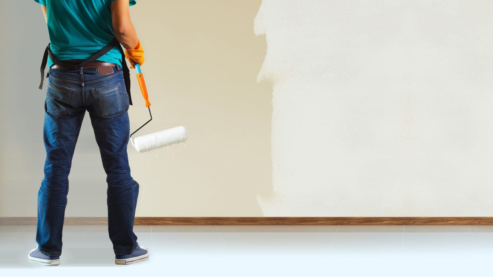 Painter with roller applying fresh paint to an interior wall