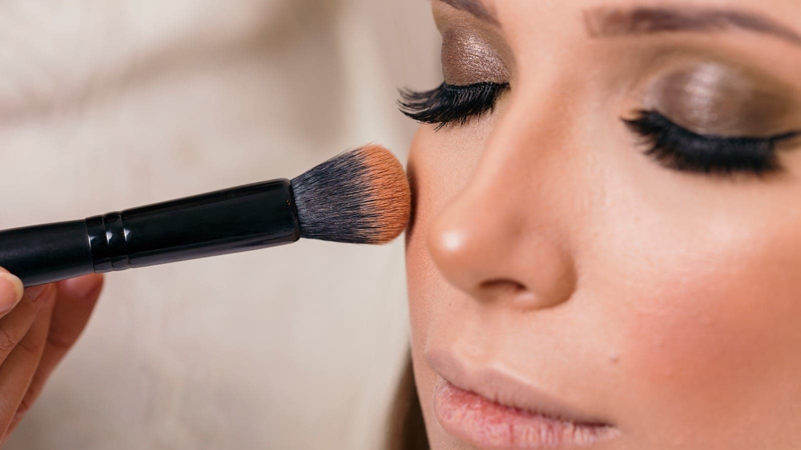 Make-up artist applying foundation to a client's face with a brush