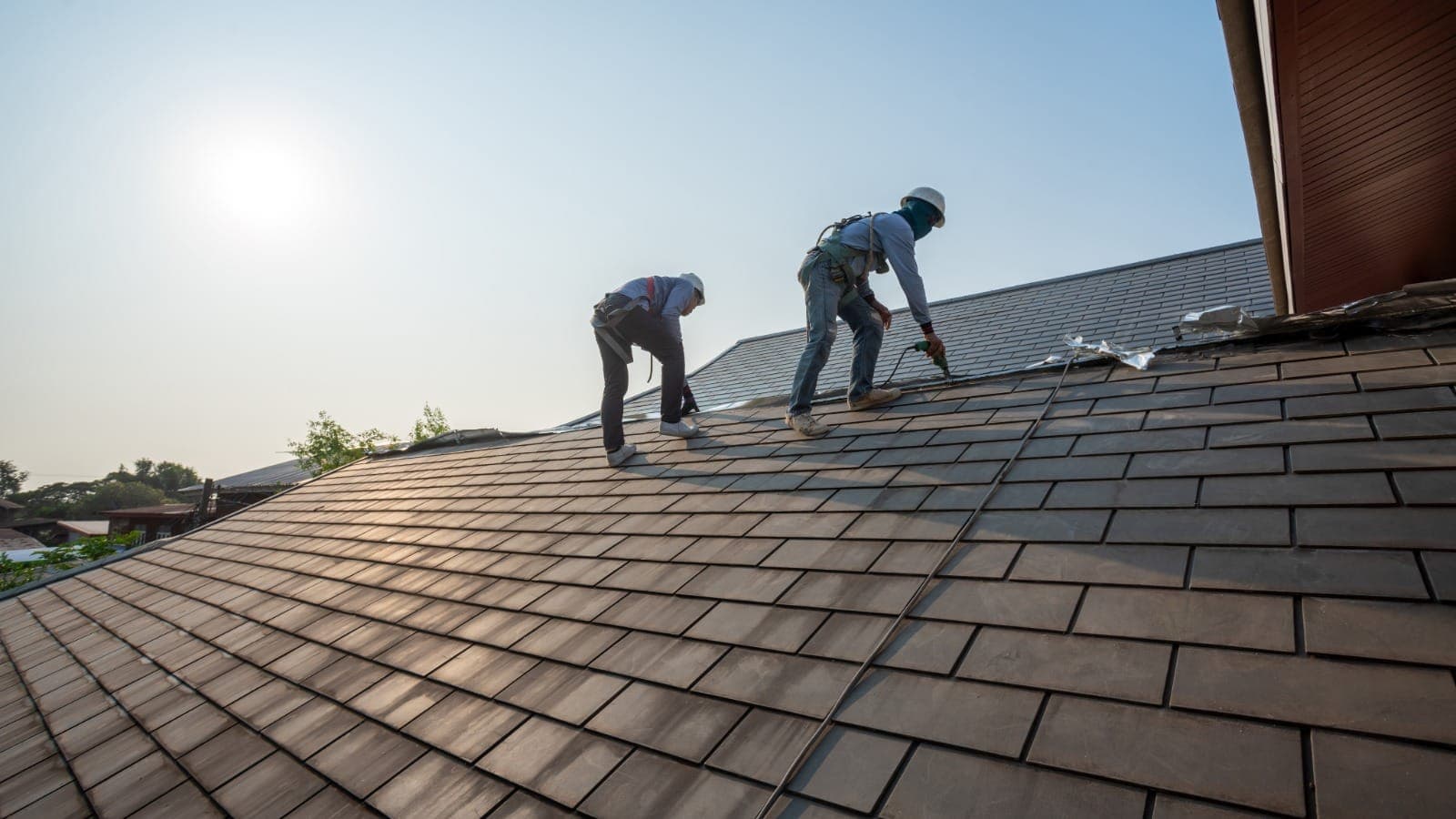 Two roofers installing tiles on a residential roof